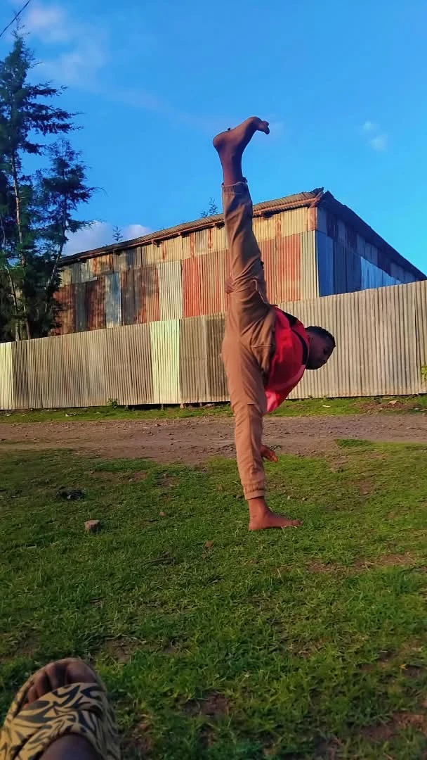Athlete in a red top practicing a high kick on grass
